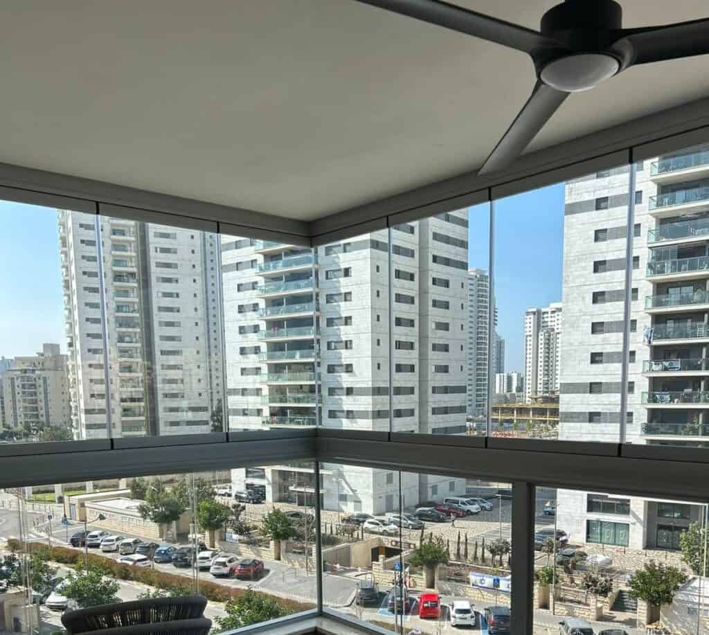 סגירת מרפסת עם חלון זכוכית שקוף נוף עירוני עם בניינים גבוהים ומאורר תקרה
